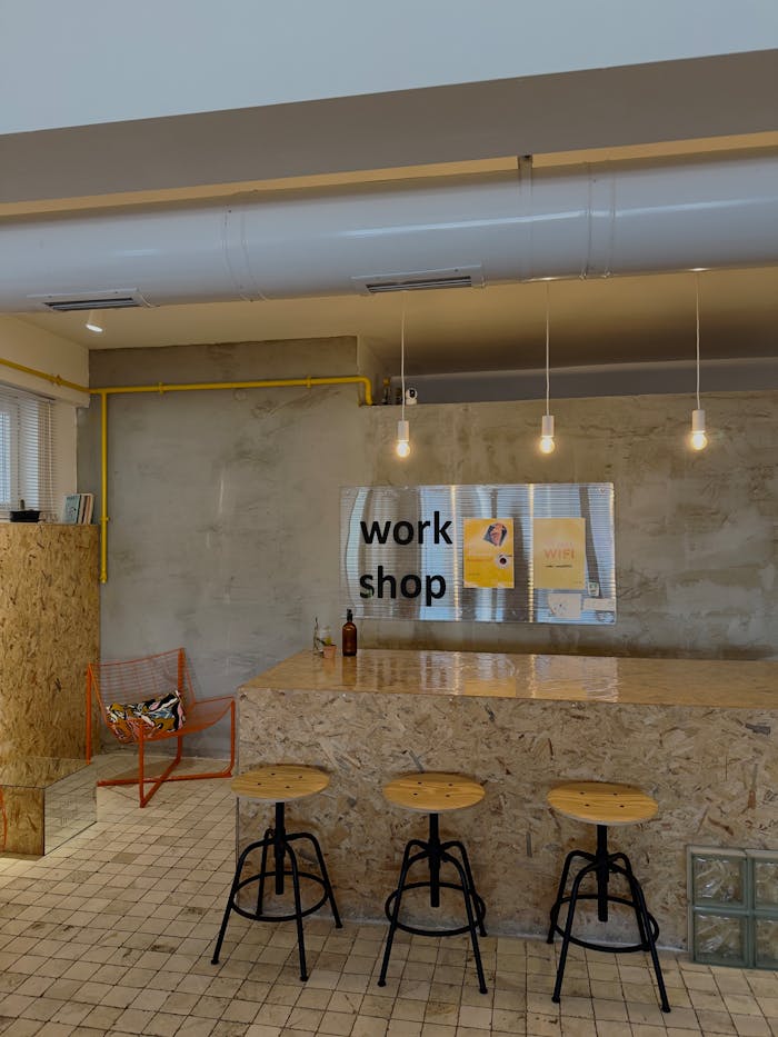 Stylish modern industrial workshop interior featuring wooden counters and stools with ambient lighting.